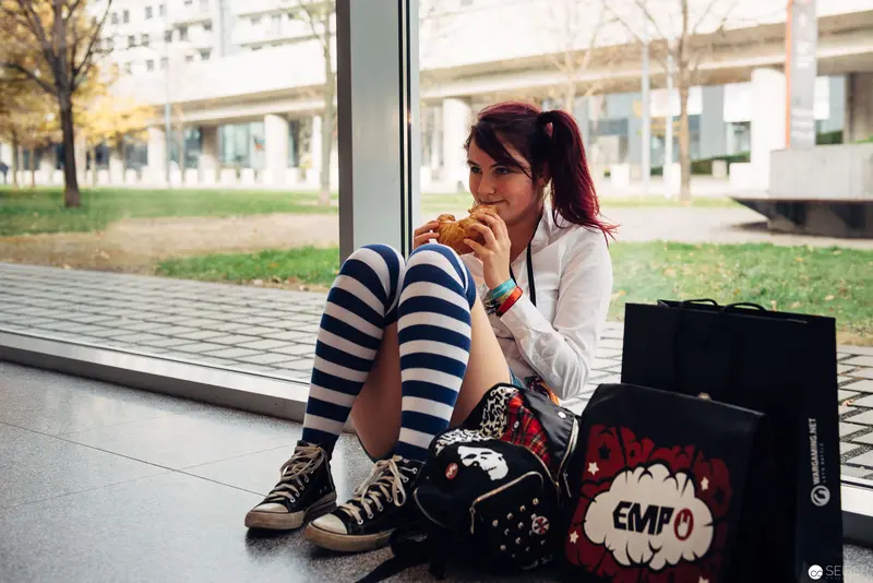 Young Woman in Striped Socks Resting by Window with Shopping Bags