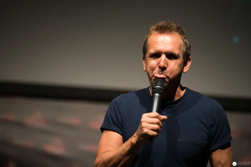 Performer Singing into Microphone on Dimly Lit Stage in Monochromatic Blue Tones