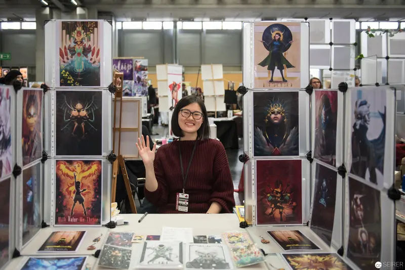 Artist at Convention Displaying Vibrant Fantasy Illustration Portfolio