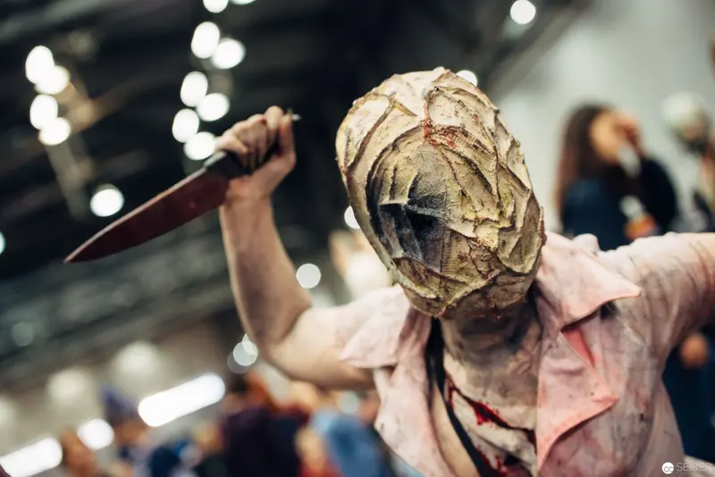 Masked Cosplayer with Knife in Distressed Costume at Fan Convention
