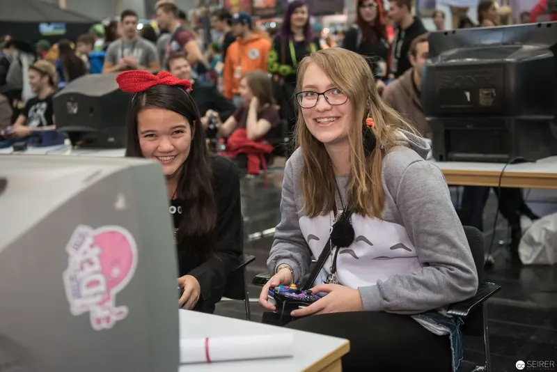 Two Young Women Participating in Gaming Event with Playful Engagement