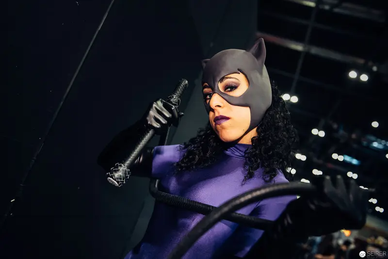 Costumed Performer in Catwoman Attire Wielding Prop at Nighttime Event