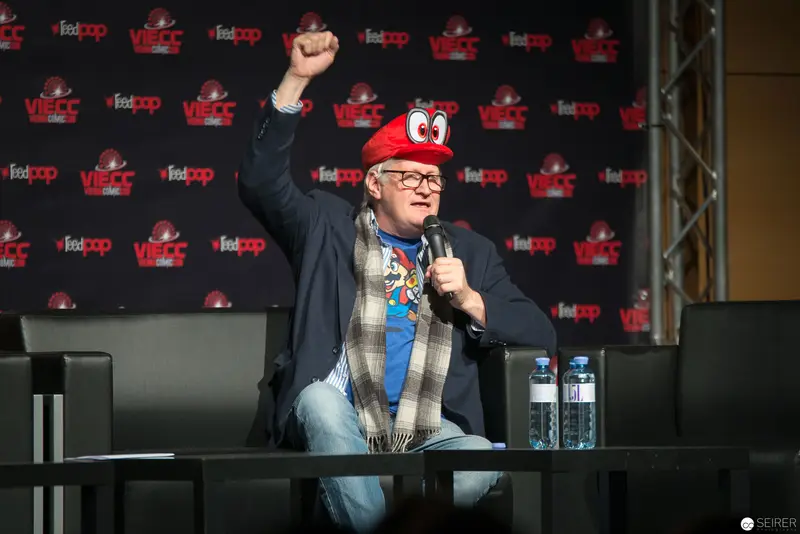 Animated Speaker at Fan Convention Raises Fist in Enthusiastic Gesture
