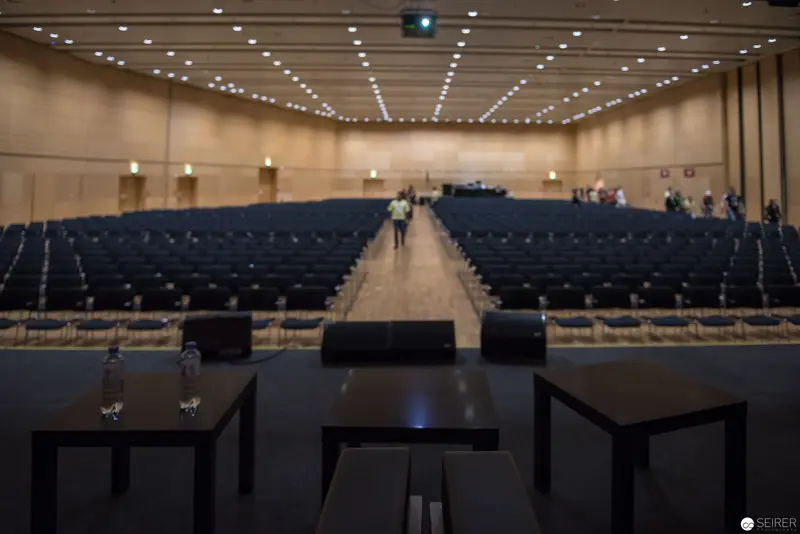 Empty Conference Hall with Radial Ceiling Lights and Central Aisle