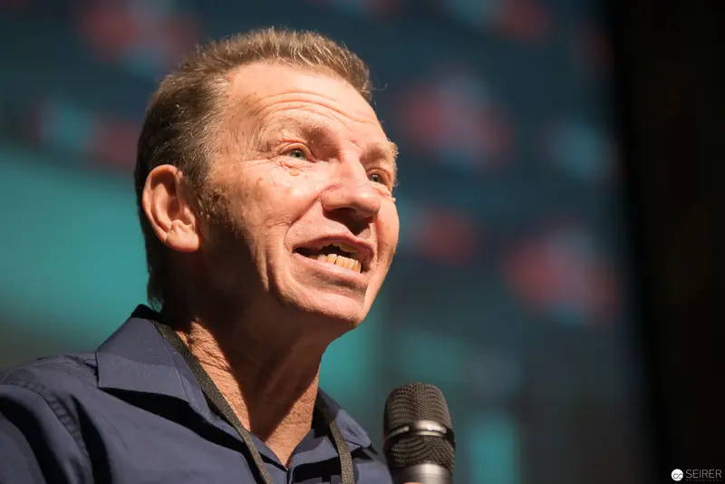 Middle-Aged Male Speaker Addressing Audience with Microphone on Stage