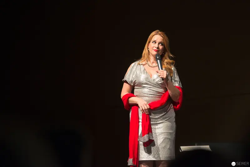 Woman in Silver Dress Performing Monologue on Dark Stage with Red Accent