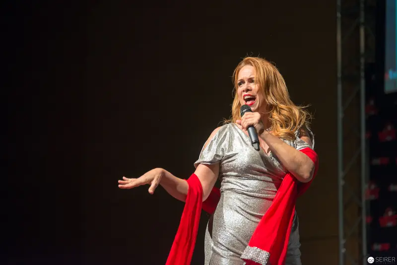Performer in Shimmering Silver Dress Delivers Energetic Stage Performance with Red Accent