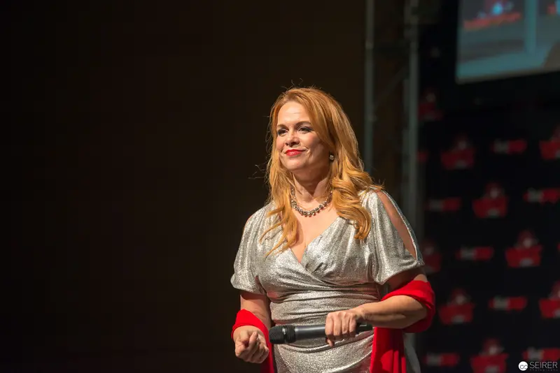 Speaker in Silver Wrap Dress Presenting at Conference Stage