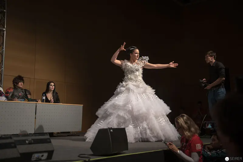 Performance Stage Gesture: Performer in Elaborate White Dress at Public Event