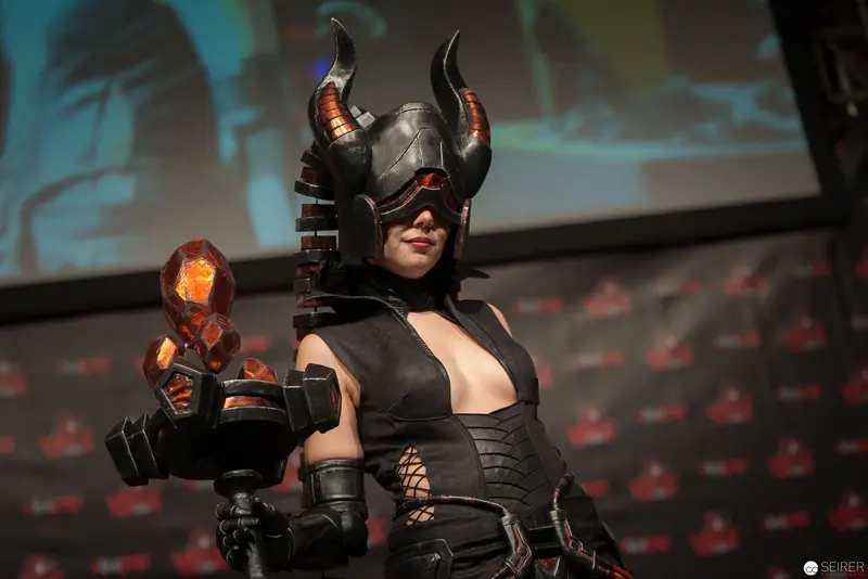 Cosplayer in Horned Helmet Wielding Glowing Prop at Convention Stage