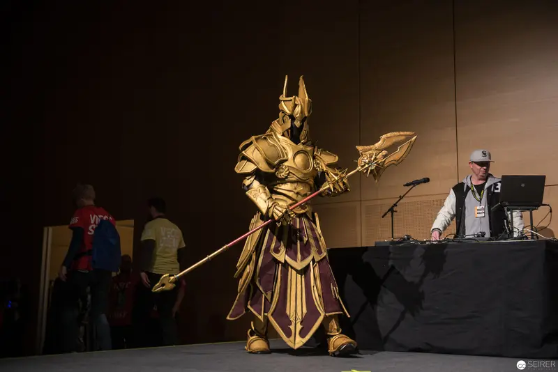 Golden Armored Warrior in Cosplay Performance at Convention Stage
