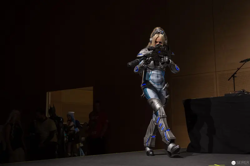 Futuristic Performer in Mechanical Exoskeleton Navigating Dimly Lit Stage