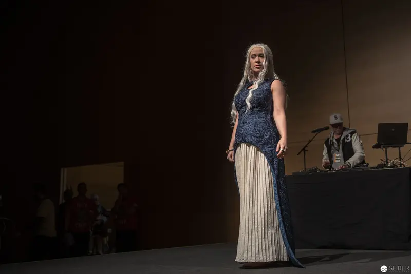 Costumed Figure on Dimly Lit Stage with Technical Backdrop