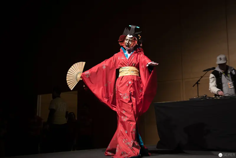 Performer in Vibrant Red Kimono with Fan on Stage during Traditional Theater Performance