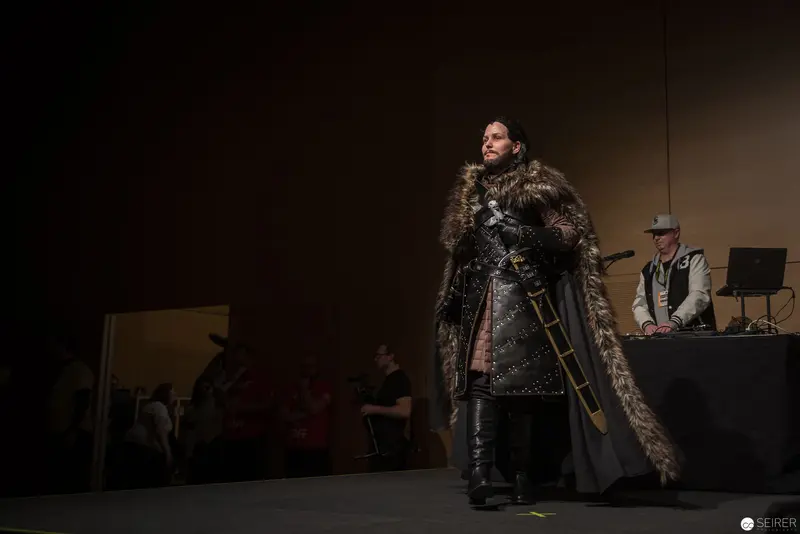Medieval-Inspired Costumed Figure on Dark Stage with Performance Backdrop