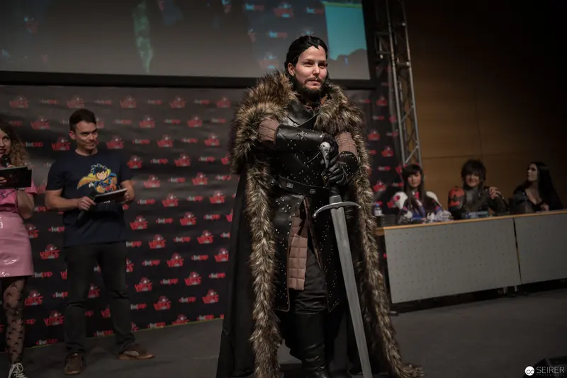 Costumed Performer in Fur-Trimmed Cape at Convention Presentation Stage