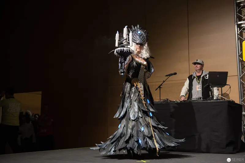 Elaborate Feathered Costume Performance at Technical Event with DJ Station