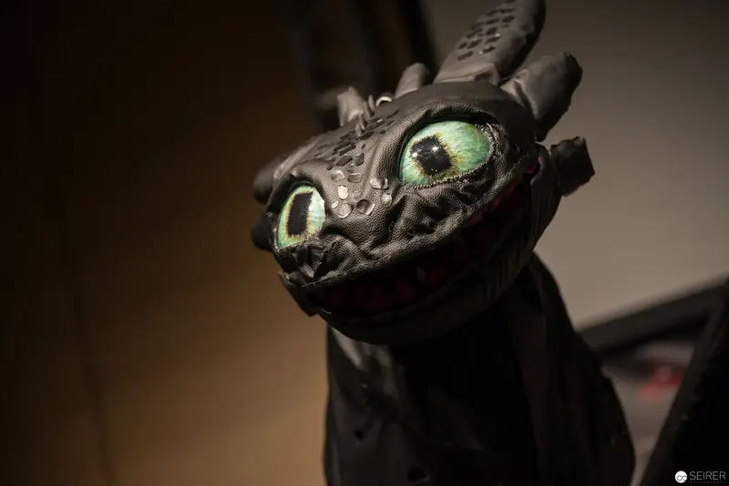 Textured Black Dragon Sculpture with Luminescent Green Eyes in Dramatic Lighting