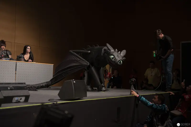 Toothless the Dragon Performing on Dimly Lit Stage with Audience and Crew
