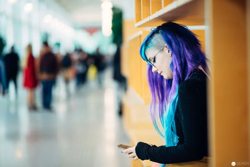 Solitary Figure with Vibrant Blue-Purple Hair in Public Space