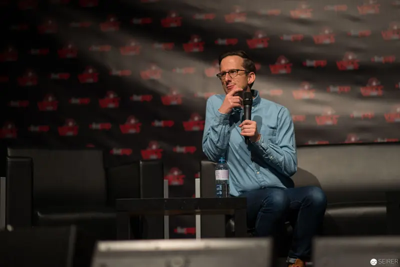 Presenter in Blue Shirt Speaking at Conference Microphone Stage