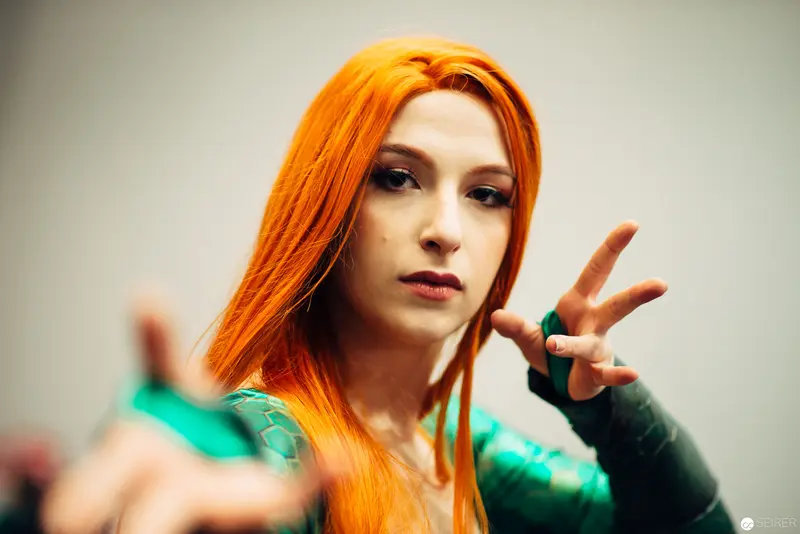 Performer with Vibrant Orange Hair Gesturing in Studio Portrait
