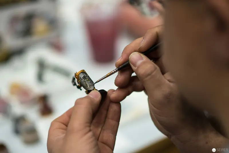 Artisan Meticulously Painting Miniature Model with Fine Brush Technique