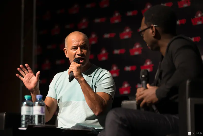 Bald Speaker Gesturing During Panel Discussion at Media Event