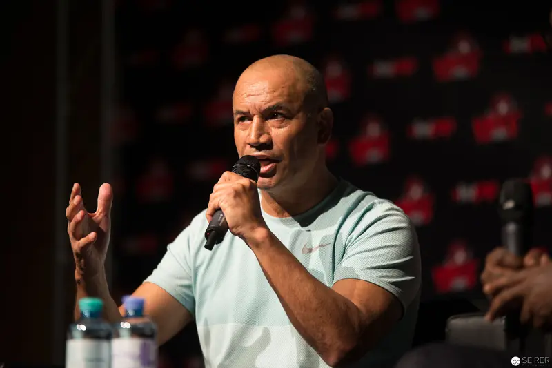 Bald Speaker Gesturing Passionately During Press Conference or Panel Discussion