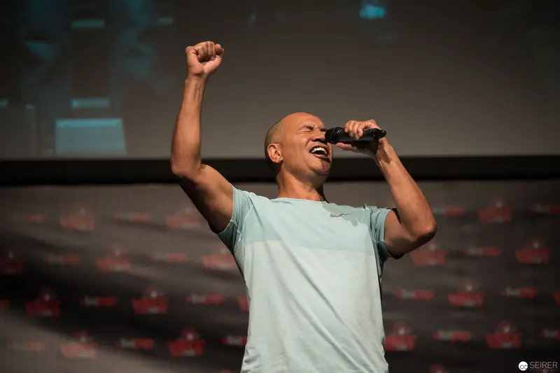 Dynamic Performance: Speaker Raises Fist During Passionate Presentation Moment