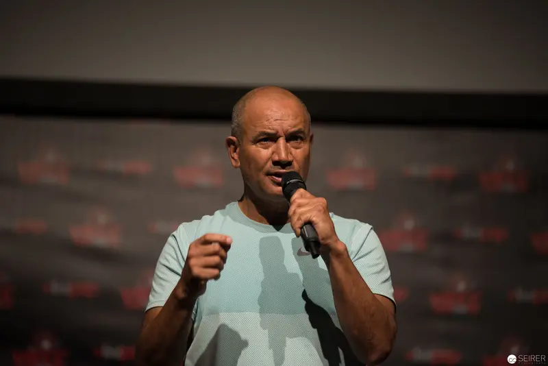 Bald Speaker Gesturing Emphatically During Public Presentation