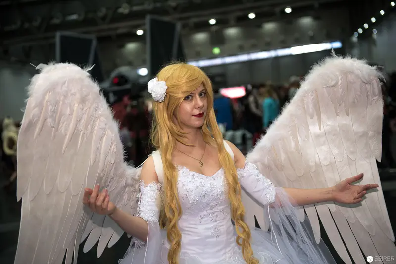 Cosplay Angel in White Dress with Elaborate Feathered Wings at Convention