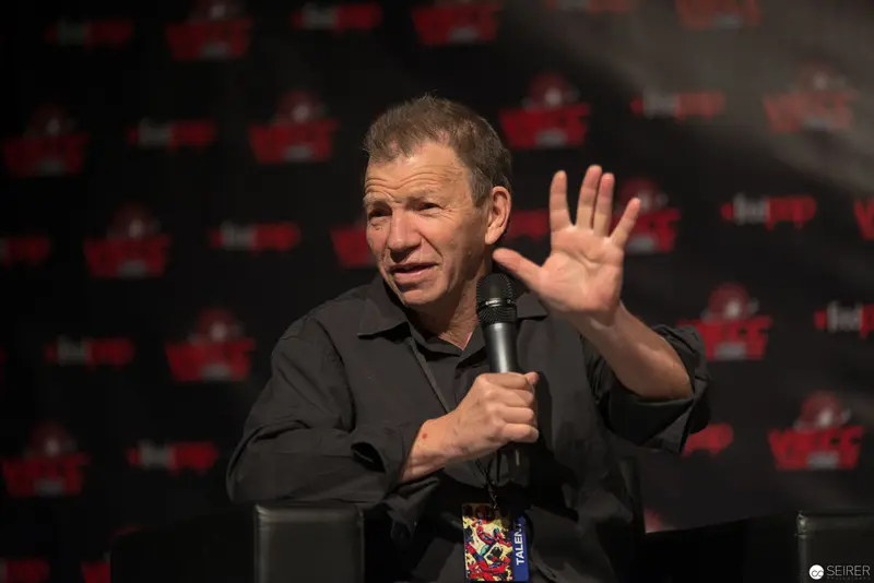 Performer Gesturing with Microphone at Convention Event Backdrop