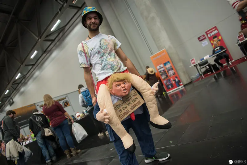 Cosplayer Carrying Satirical Caricature Puppet at Convention Hall