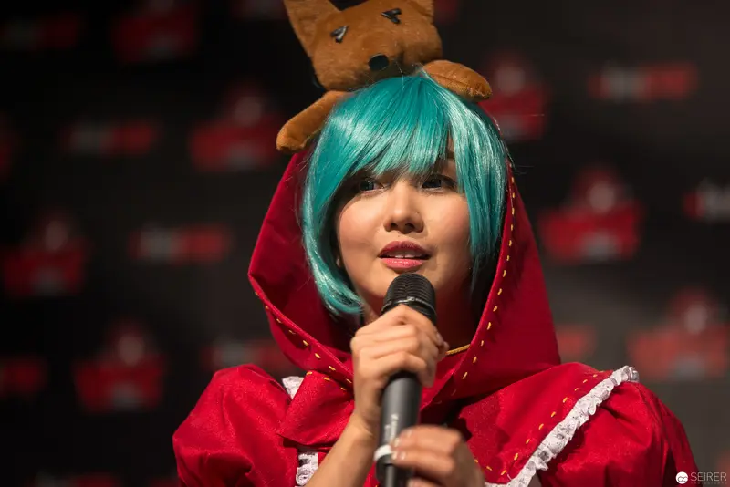 Cosplay Performance with Teal-Haired Performer in Red Hooded Costume