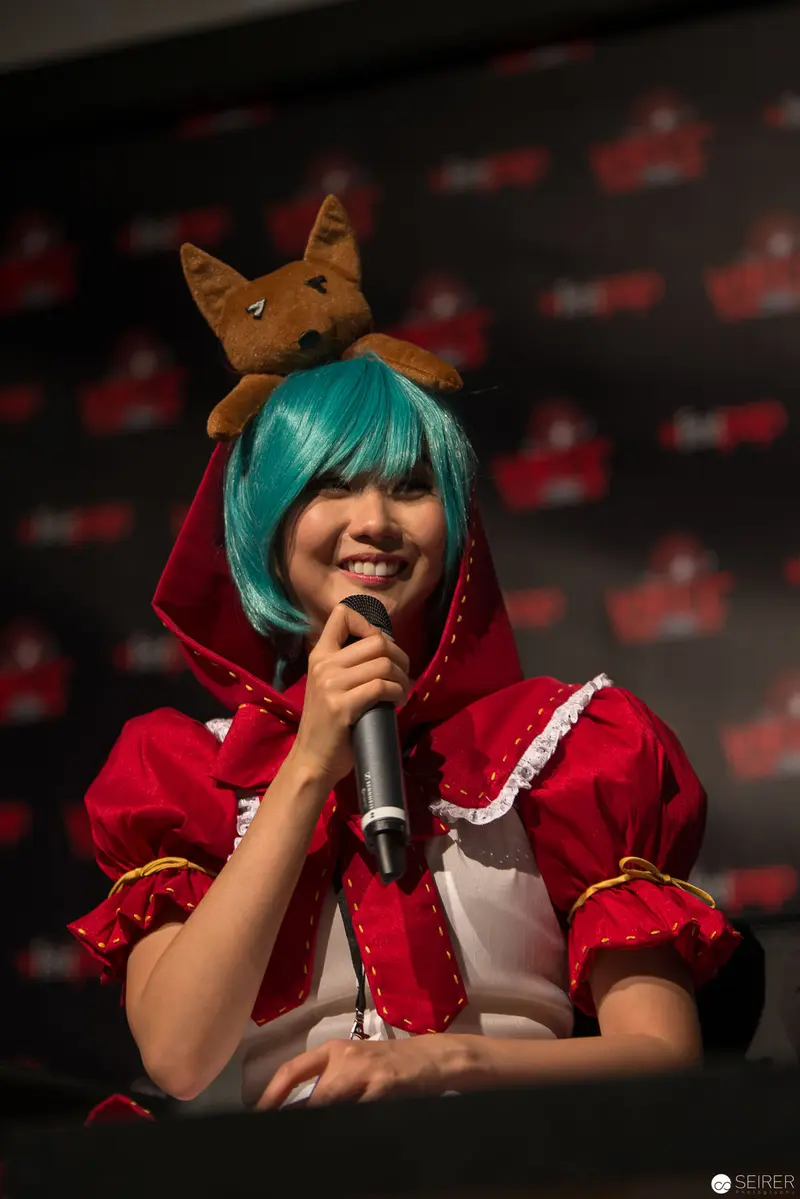 Costumed Performer with Turquoise Hair Speaks at Themed Convention
