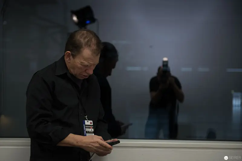 Solitary Figure Examining Device in Dimly Lit Institutional Space