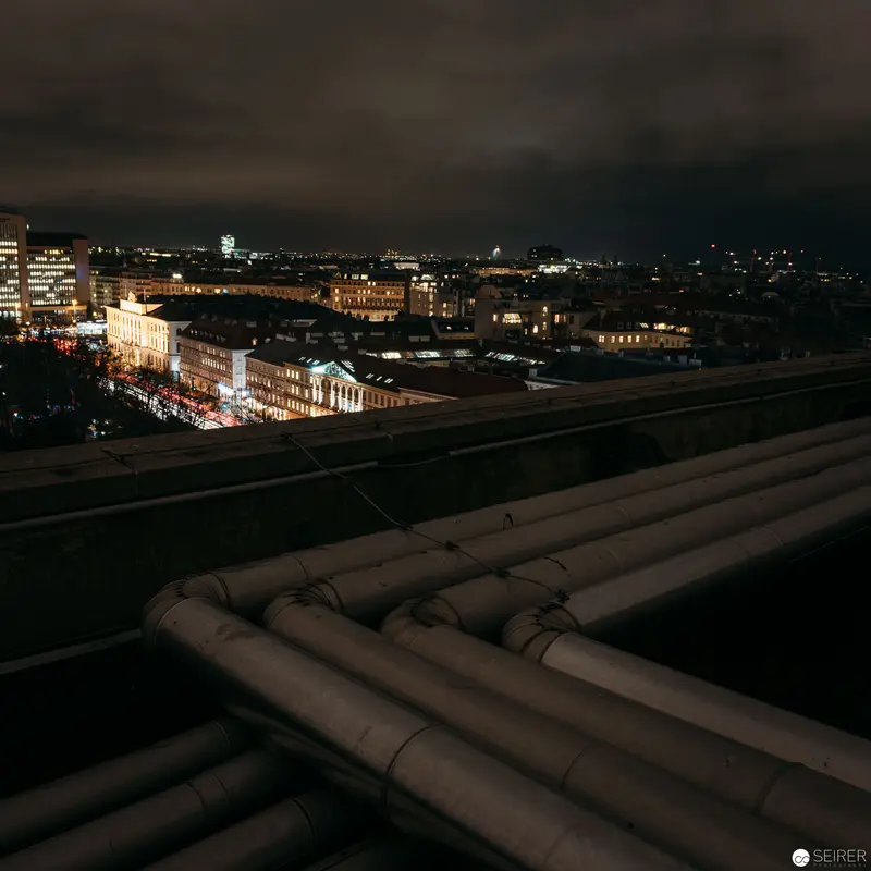 Nocturnal Urban Landscape with Industrial Pipelines Overlooking Illuminated Cityscape