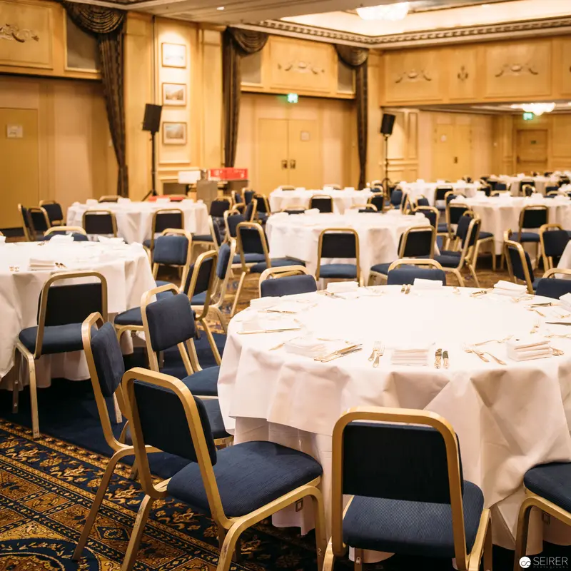 Elegant Banquet Hall with White-Clothed Tables and Blue Upholstered Chairs