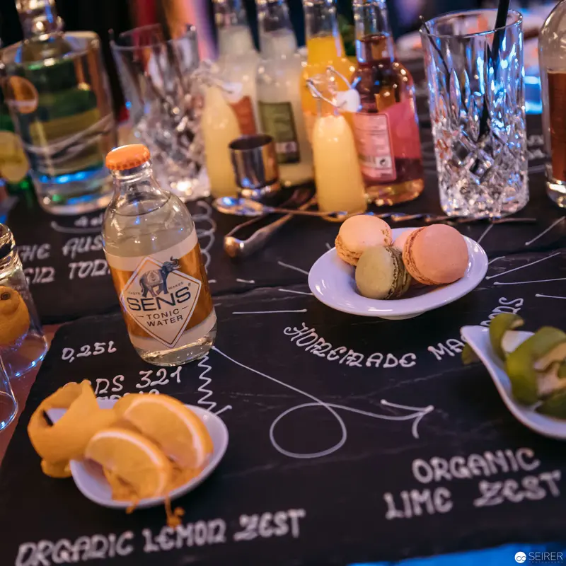 Artisanal Bar Setup with Craft Beverage and Macarons on Chalkboard Menu