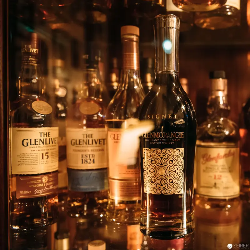 Rare Scotch Whisky Collection: Glenlivet and Glenmorangie Bottles in Warm Lighting
