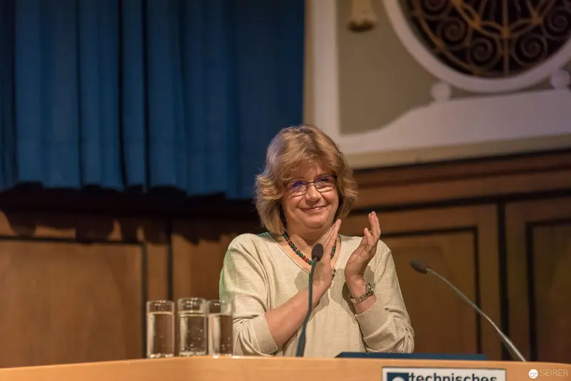 Speaker Applauding at Technical Conference Podium with Glasses and Microphone