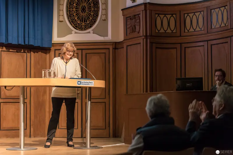 Scholarly Lecture at Ornate Wood-Paneled Hall with Presenter at Podium