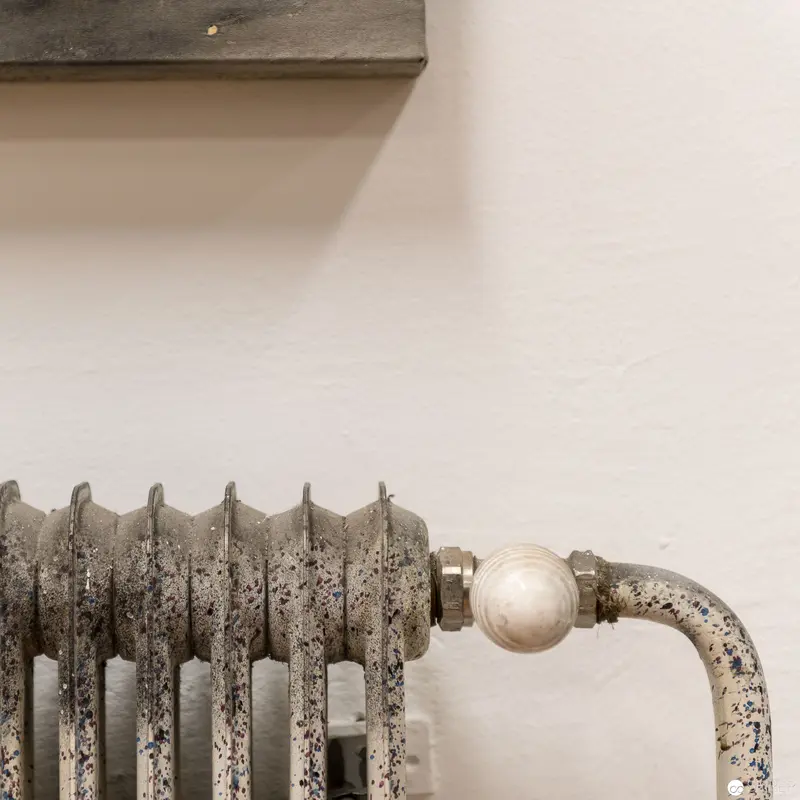 Aged Cast Iron Radiator with Weathered Surface Against Neutral Wall