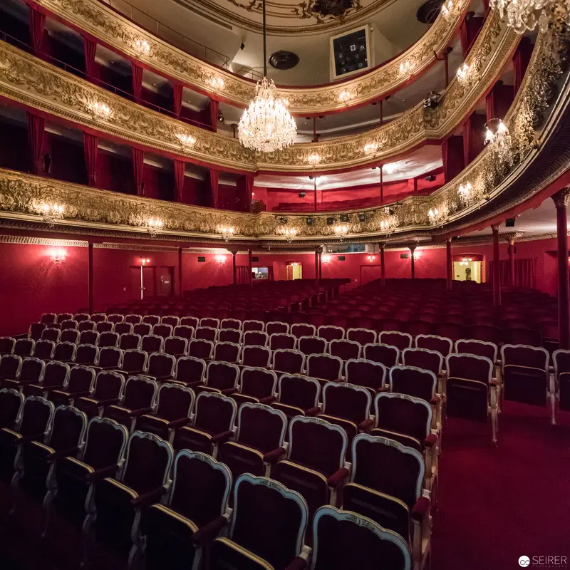 Opulent Red and Gold Theatre Interior with Ornate Baroque Chandelier and Empty Seats