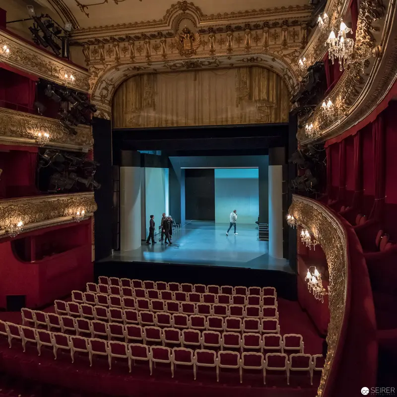 Ornate Theatre Interior with Minimalist Stage Performance in Blue Lighting