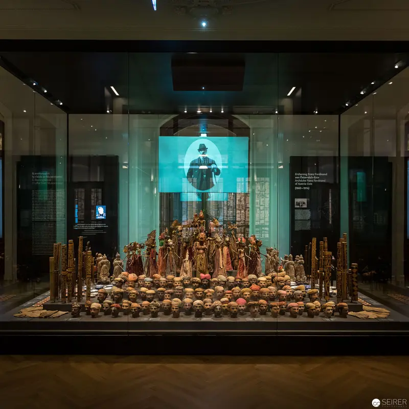 Museum Installation Displaying Intricate Historical Ceramic Figurines with Projected Imagery