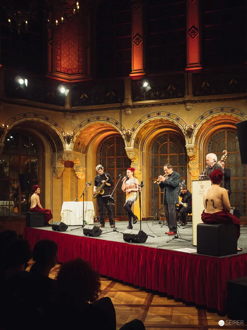 Musical Performance in Ornate Historical Venue with Arched Windows and Red Drapery