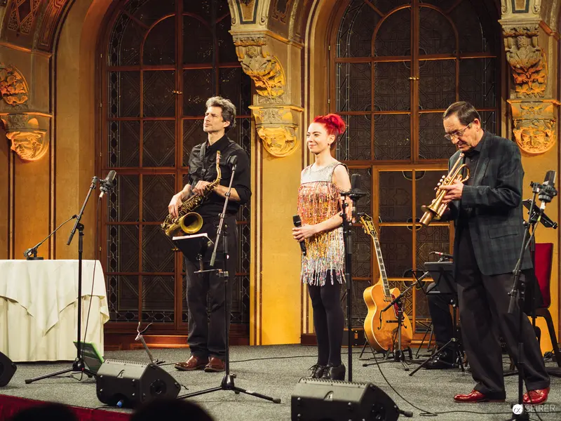 Jazz Trio Performance in Ornate Historical Interior with Saxophone, Voice, and Trumpet