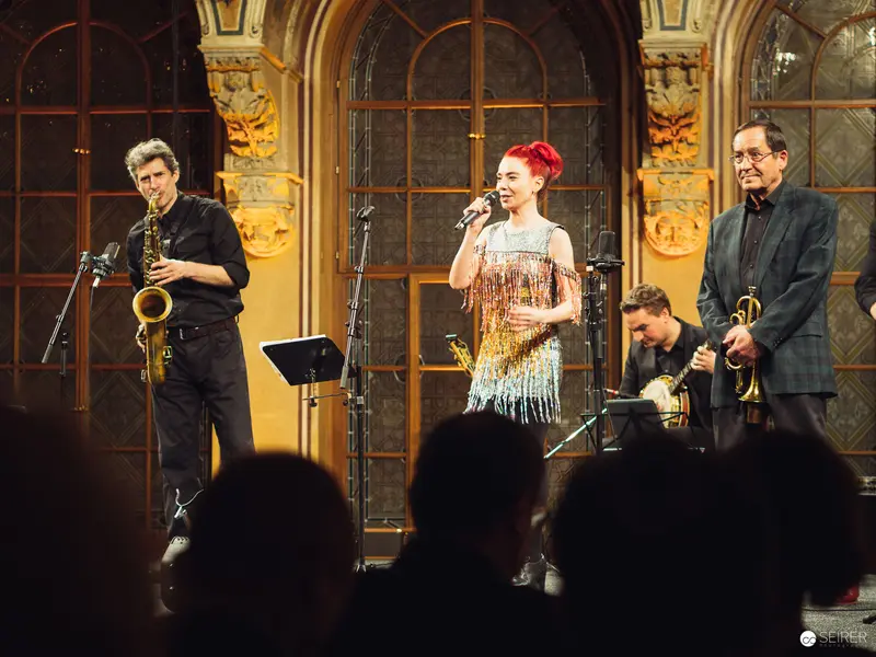 Jazz Ensemble Performance in Ornate Concert Hall with Vocalist in Sequined Dress